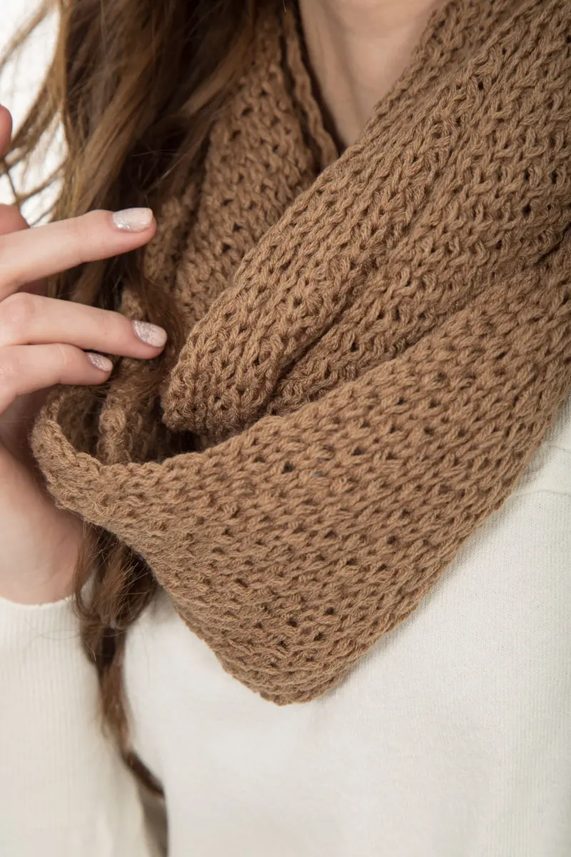 A caramel textured knitted cowl draped around a person's neck